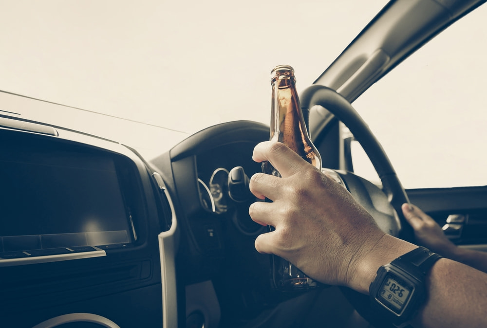 Driver holding a beer bottle while operating a vehicle
