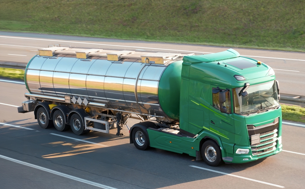 Green tanker truck driving on a multi-lane highway