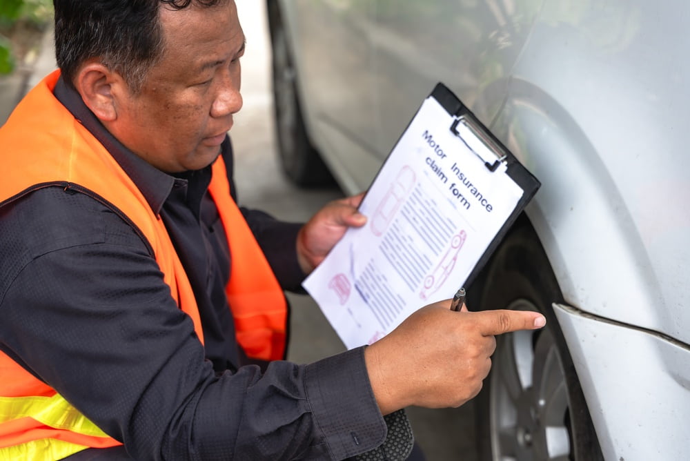 person examining and documenting damage to a vehicle