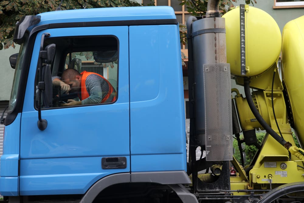 driver tired inside a parked blue truck while checking his phone